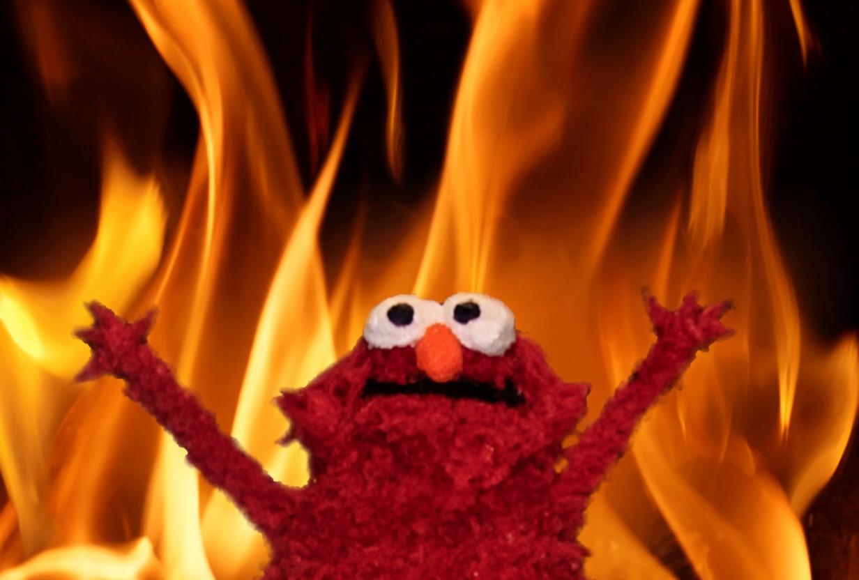 A red fuzzy Elmo puppet faces the camera with both arms raised high, wide white eyes, an orange nose, and an open black mouth. Behind him fills the frame with large, bright orange and yellow flames against a dark background.