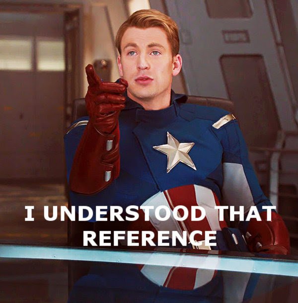 A man in a blue Captain America superhero costume with a silver star on the chest, red gloves, and a red-white-and-blue shield rests at a desk or console. He looks toward the viewer, points forward with his right index finger, and has a knowing, slightly open-mouthed expression. Large white capital text with a dark outline sits across the lower portion of the image.
