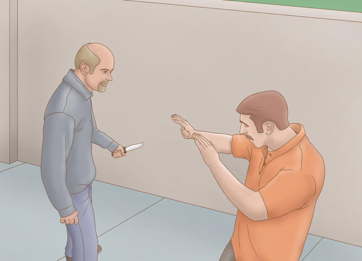 A bald man with a goatee in a blue sweater stands on the left holding a knife at his side. On the right, a man in an orange polo raises both hands in a defensive stop/guard pose. They face each other in a plain indoor hallway with beige walls and light tile floor. No captions are on the image yet.