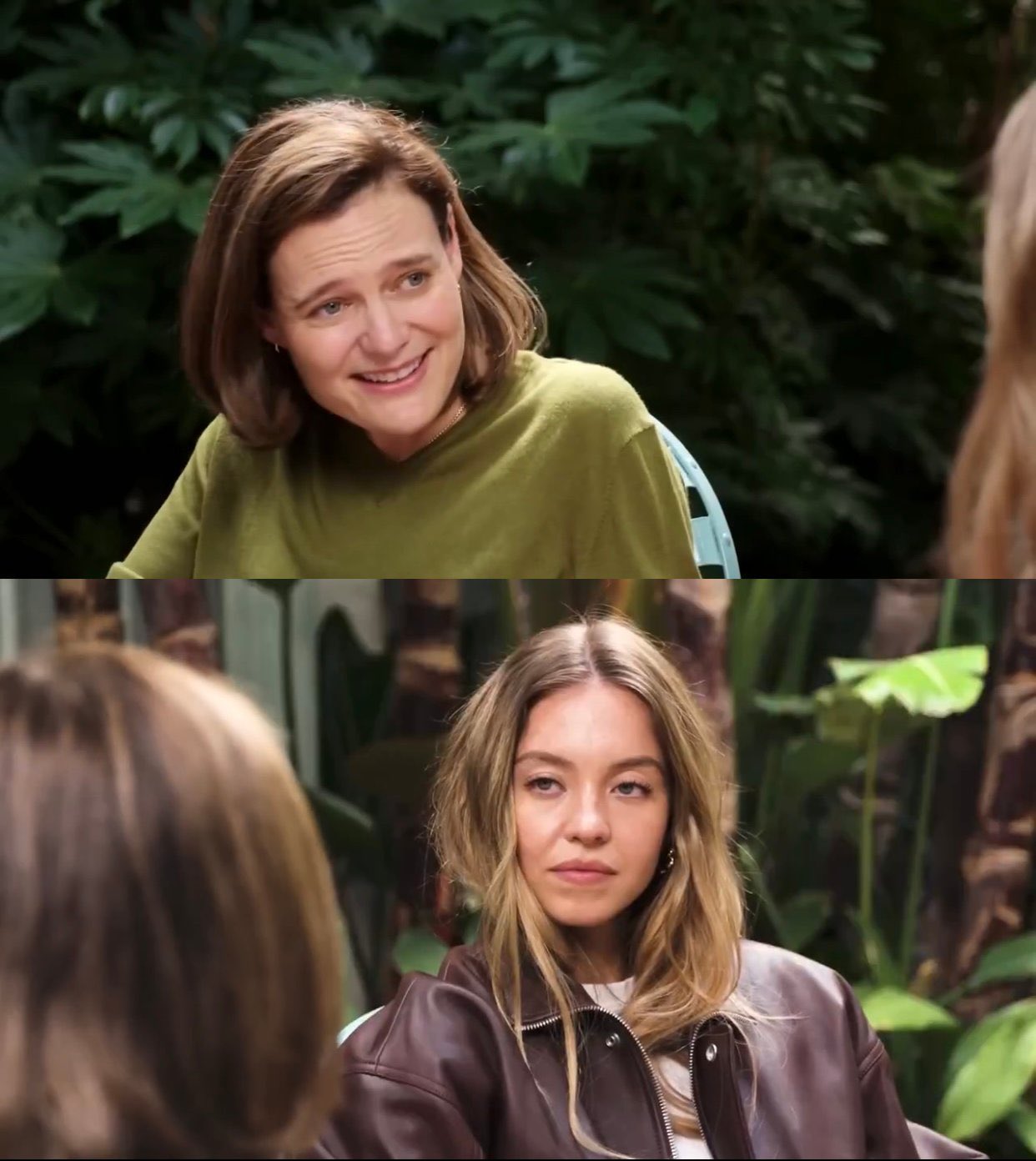 Two-panel photo layout. Top panel: a woman with shoulder-length brown hair in a lime-green sweater sits outdoors among dense green foliage, leaning forward, smiling broadly with raised brows while speaking toward someone off-frame to the right. Bottom panel: a young woman with long wavy blonde hair in a dark brown leather jacket sits facing slightly left among large tropical leaves, looking back with a flat, unsmiling, unimpressed expression; the back of another person’s head is visible in the foreground left.